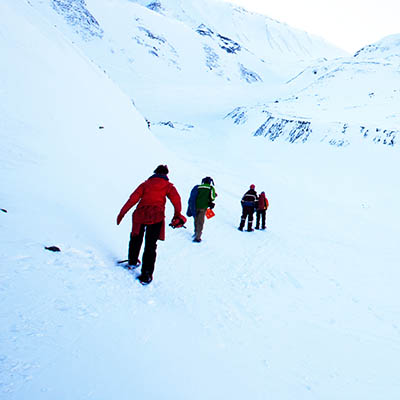 Group of people hiking across a winter landscape in Svalbard