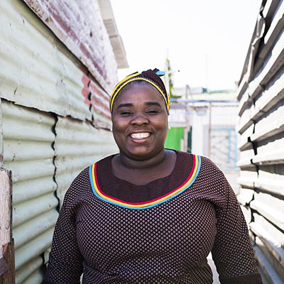 Smiling black woman standing outside in a township in South Africa