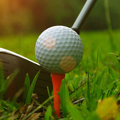 Golf club and golf ball close up in grass field at sunset