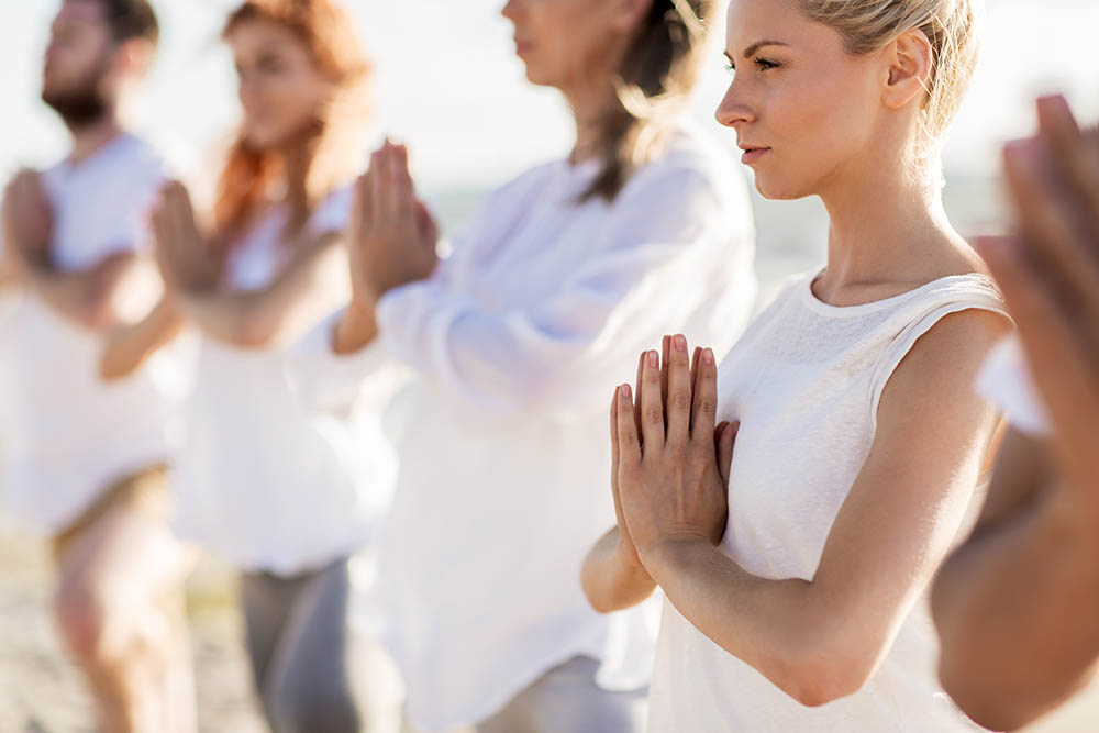 Group of people practising yoga on the beach