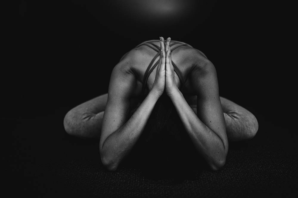 Black & white image of woman in yoga pose on wooden floor