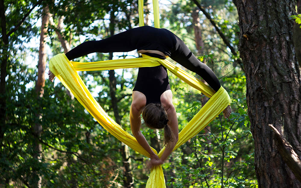 Young woman doing aerial yoga in a forest