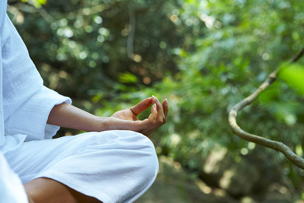 young woman practicing yoga in tropical environment