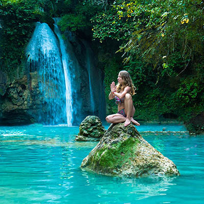 Young woman practicing yoga next to Kawasan Falls, Cebu Island, Philippines