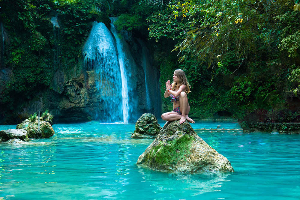 Young woman practicing yoga next to Kawasan Falls, Cebu Island, Philippines