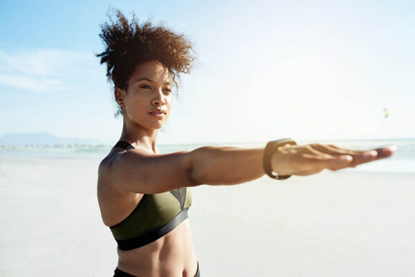 Shot of a fit young woman doing yoga at the beach