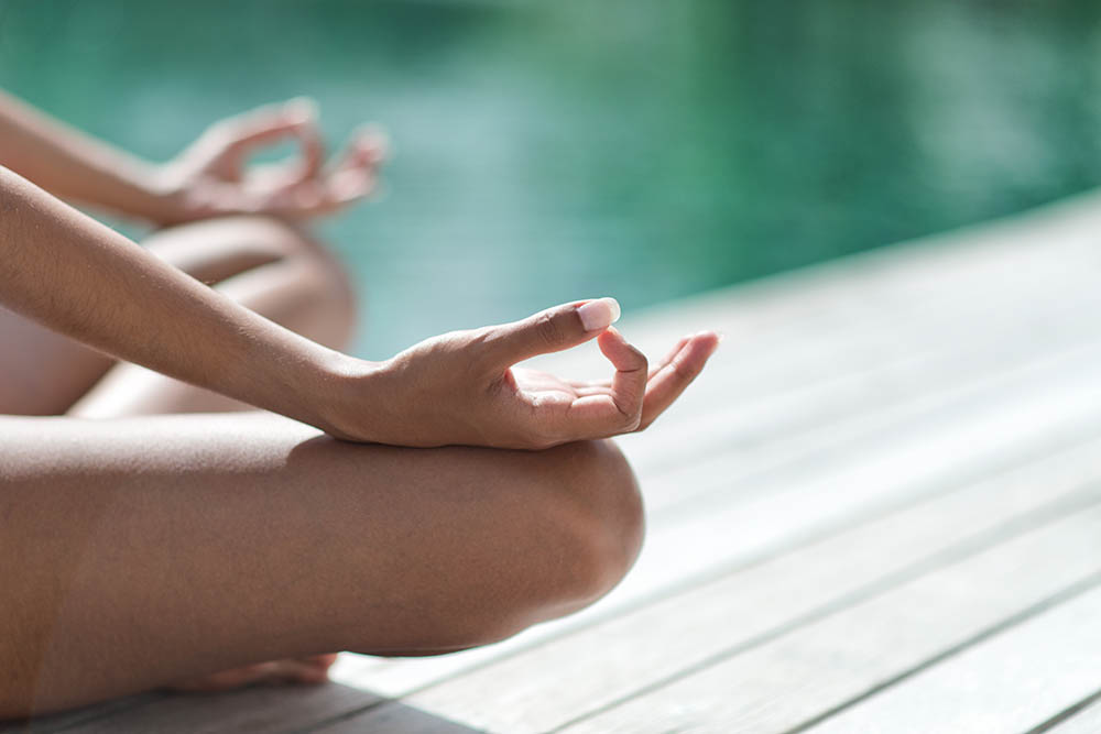 Young woman meditating on a wooden jetty