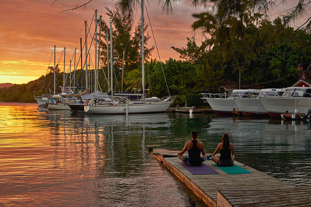 Couple sitting in yoga pose on a jetty in Roatan, Bay islands, Honduras