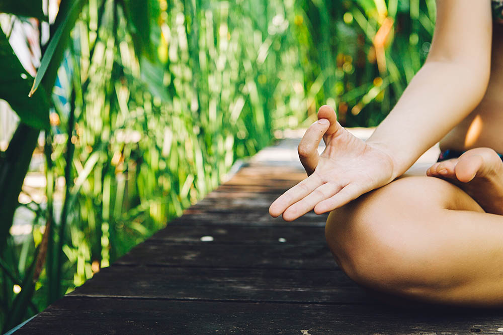 Close up of woman practicing yoga with green grass jungle background