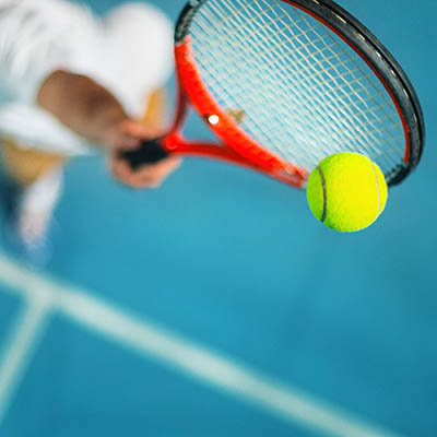 Closeup high angle view of male tennis player hitting a ball against blue court