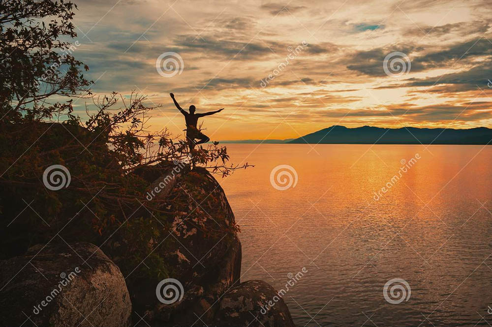 Girl in yoga pose at sunset on Lake Malawi