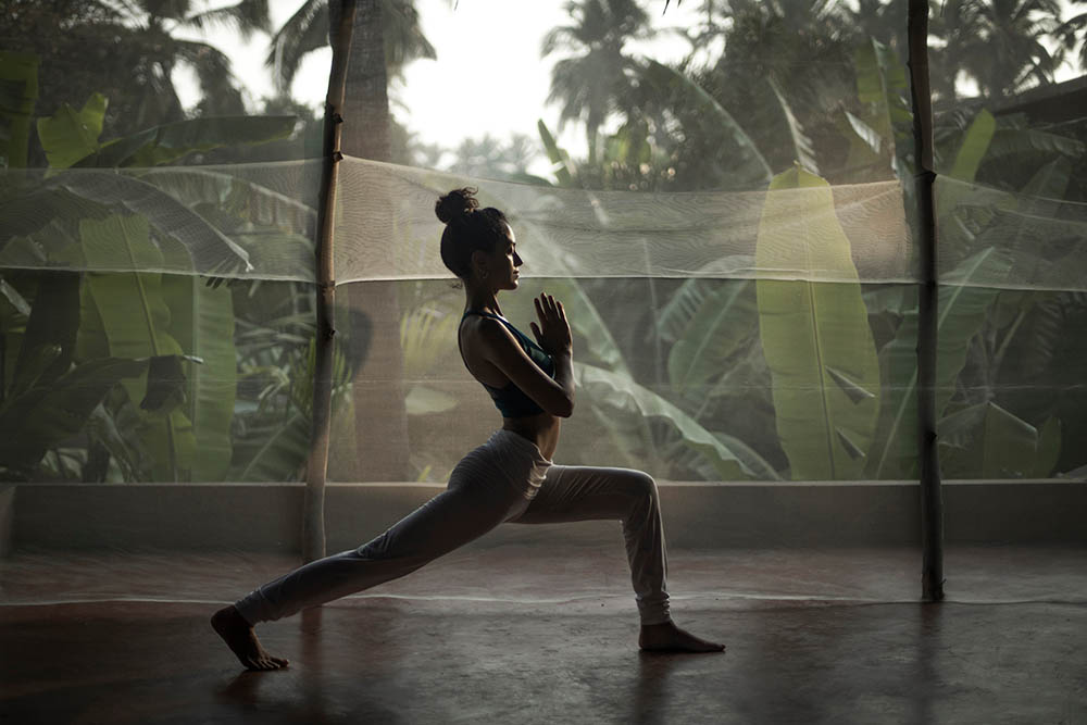 Young woman practicing yoga in an open studio in a tropical setting