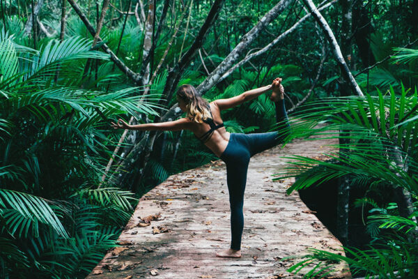 Woman doing yoga on tropical forest