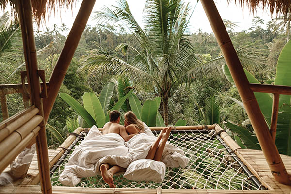 Happy couple on hammock of tree house with jungle nature view on honeymoon on Bali